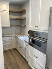 Kitchen featuring light stone counters, white cabinetry, dark hardwood / wood-style floors, and oven