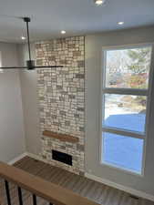 Unfurnished living room with a stone fireplace and hardwood / wood-style floors