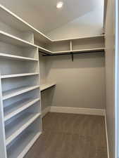 Walk in closet featuring lofted ceiling and dark carpet