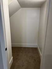 Interior space featuring dark colored carpet and vaulted ceiling