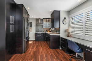 Kitchen featuring sink, wall chimney range hood, light stone counters, and dark hardwood / wood-style flooring