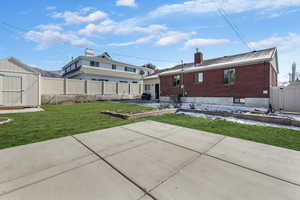 Rear view of house featuring a storage shed, a patio, and a lawn