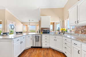 Kitchen featuring pendant lighting, white cabinetry, dishwasher, sink, and kitchen peninsula