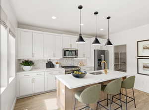 MODEL      Kitchen featuring a kitchen island with sink, appliances with stainless steel finishes, light countertops, and a sink