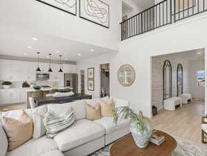 MODEL   Living area with light wood-style floors, recessed lighting, a towering ceiling, and baseboards