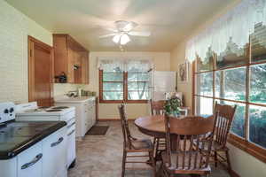 Kitchen with sink, white appliances, ceiling fan, brick wall, and light tile patterned flooring