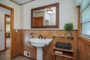 Bathroom featuring crown molding and wooden walls