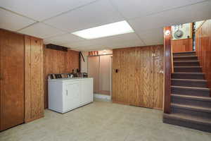 Laundry room with wooden walls and separate washer and dryer