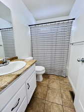 Full bathroom with vanity, tile patterned floors, toilet, and shower / tub combo with curtain