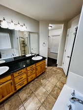 Bathroom with vanity, tile patterned flooring, shower with separate bathtub, and a textured ceiling