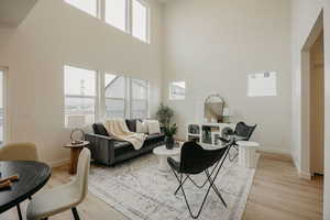 Living area with light wood-style flooring, a high ceiling, and baseboards