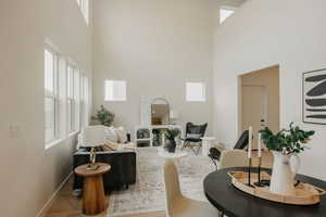 Living area featuring a towering ceiling, baseboards, and a wealth of natural light