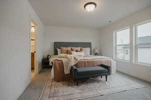 Bedroom featuring light carpet, connected bathroom, and baseboards