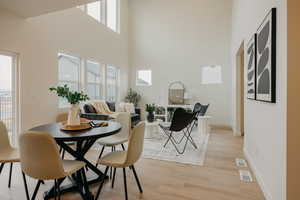 Dining area featuring a high ceiling, baseboards, visible vents, and light wood finished floors