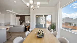 Dining room featuring wood-type flooring, a textured ceiling, an inviting chandelier, and a tray ceiling