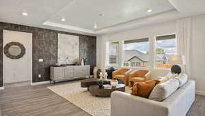 Living room featuring wood-type flooring, a textured ceiling, and a tray ceiling