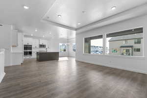 Unfurnished living room with dark wood-type flooring, a chandelier, and sink