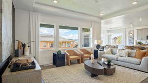 Living room with a tray ceiling, a chandelier, hardwood / wood-style floors, and a textured ceiling