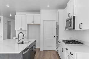 Kitchen featuring appliances with stainless steel finishes, sink, a center island with sink, and white cabinets