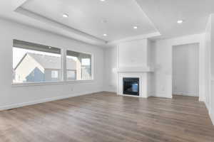 Unfurnished living room with a raised ceiling, a large fireplace, and hardwood / wood-style floors