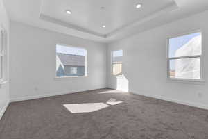 Unfurnished room featuring dark carpet and a raised ceiling