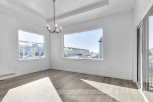 Dining area with an inviting chandelier, a tray ceiling, and hardwood / wood-style floors