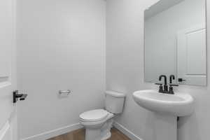 Bathroom with hardwood / wood-style flooring, toilet, and sink