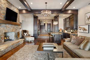 Living room with dark wood-type flooring, a fireplace, and a chandelier