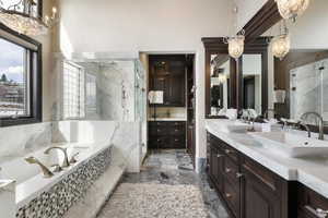 Bathroom featuring vanity, a chandelier, and plus walk in shower