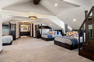 Carpeted bedroom with vaulted ceiling with beams and ensuite bath