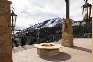 Snow covered patio with a mountain view and a fire pit