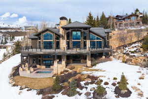 Snow covered property with a patio area, a balcony, and an in ground hot tub