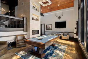 Game room with high vaulted ceiling, dark hardwood / wood-style floors, a tiled fireplace, pool table, and wooden ceiling