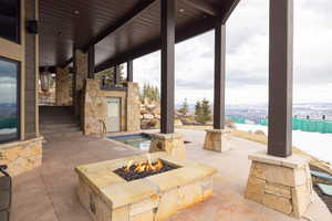 View of patio with a swimming pool and an outdoor fire pit