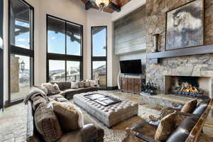 Living room with beam ceiling, ceiling fan, a fireplace, and high vaulted ceiling