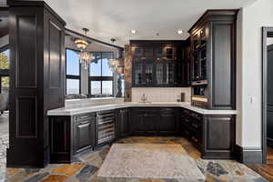 Bar featuring plenty of natural light, beverage cooler, oven, and dark brown cabinets