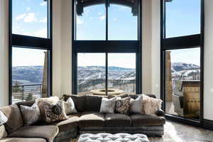 Living room with a high ceiling, a mountain view, and a wall of windows