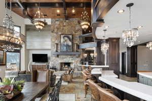 Dining space featuring a stone fireplace, wood ceiling, a chandelier, beam ceiling, and a high ceiling