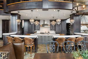 Kitchen featuring a spacious island, wall chimney exhaust hood, a kitchen breakfast bar, and pendant lighting