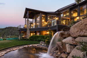 Back house at dusk featuring a yard and a balcony