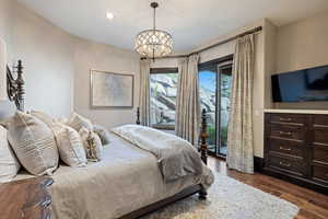 Bedroom featuring a chandelier, access to exterior, and dark hardwood / wood-style flooring