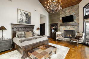 Bedroom with wood ceiling, a chandelier, high vaulted ceiling, hardwood / wood-style flooring, and a fireplace