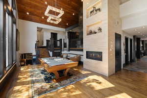 Playroom with hardwood / wood-style floors, a high ceiling, a tiled fireplace, pool table, and wooden ceiling