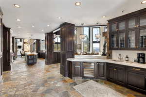 Kitchen with an inviting chandelier, dark brown cabinets, sink, and hanging light fixtures