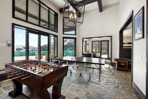 Rec room with plenty of natural light, a chandelier, a high ceiling, and a water view