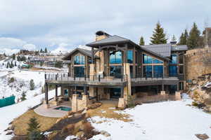 Snow covered property featuring a hot tub, a deck, and a patio area