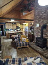 Living room featuring high vaulted ceiling, light hardwood / wood-style floors, and a wood stove