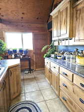 Kitchen with lofted ceiling, light tile patterned floors, wood ceiling, and wood walls