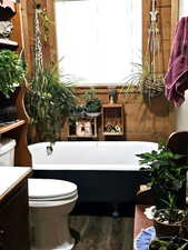 Bathroom featuring hardwood / wood-style flooring, vanity, toilet, and a  Claw foot bathing tub