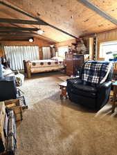 Carpeted Bedroom upstairs loft area  with beams, wooden ceiling, and wood walls